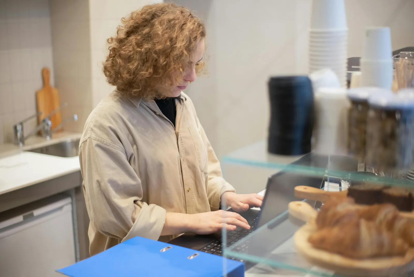 Kvinne som arbeider på en laptop bak en kafédisk
