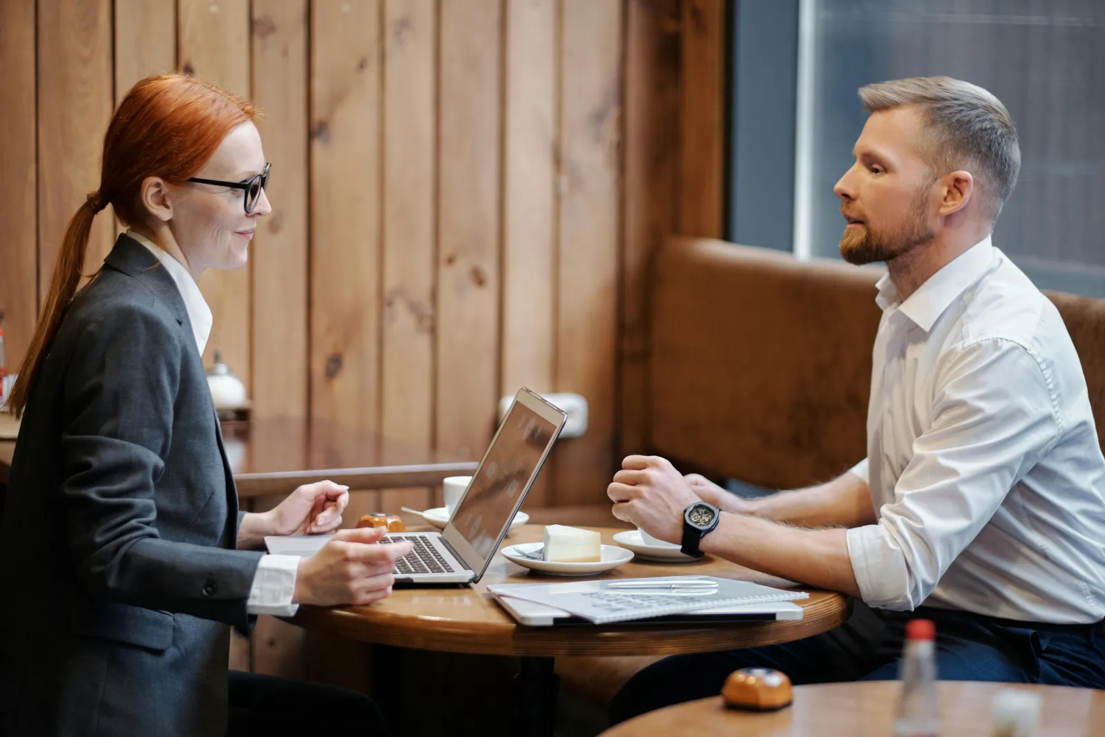 To personer i en uformell samtale over kaffe og en laptop i et lyst lokale